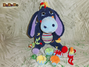 Gehäkeltes Amigurumi-Eselchen in dunklem Blau mit langen Ohren, hellblauem Maul und bunten Häkelaccessoires