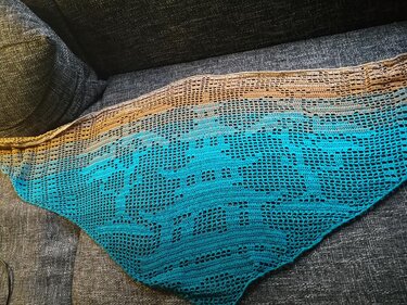 Dreieckiges gehäkeltes Tuch in Braun und Türkis mit Filetmuster und Fischmotiven auf Sofa