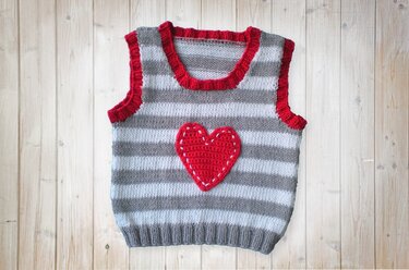 Ärmellose gestrickte Babyweste mit grauen Streifen, rotem Rand und aufgenähtem roten Herz