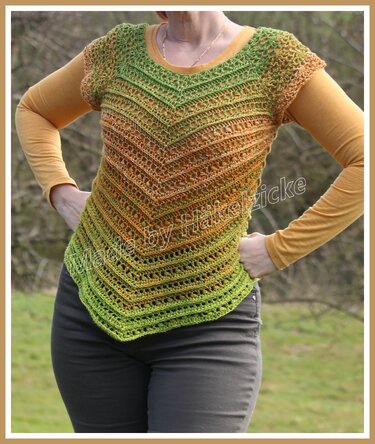 Gehäkeltes Kurzarmshirt in Grün‑Orange‑Farbverlauf mit V‑förmigem Muster über gelbem Langarmshirt