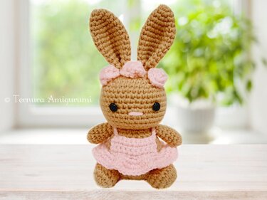 Braunes handgehäkeltes Amigurumi-Häschen mit rosa Kleid und Blüten