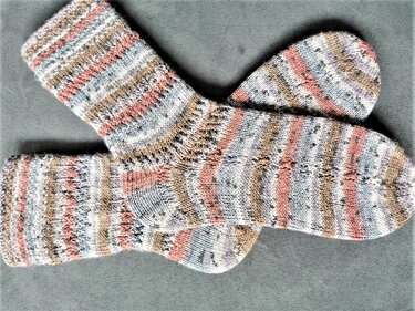Gestricktes Paar Damensocken mit Pastellstreifen auf grauem Hintergrund