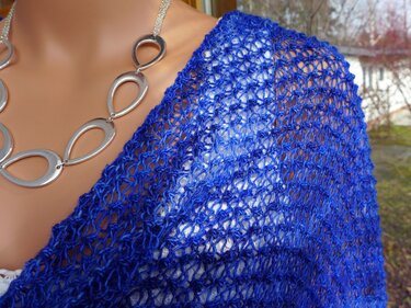 Schaufensterpuppe mit blauem Strickponcho im offenen Lochmuster und silberner Kette