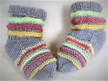 Gestrickte Neugeborenen-Socken in Grau mit pastellfarbenen Streifen und Rippbündchen
