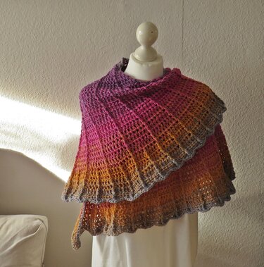 Halbrundes gehäkeltes Tuch in Violett‑Pink‑Orange mit Muschelrand auf Ankleidepuppe
