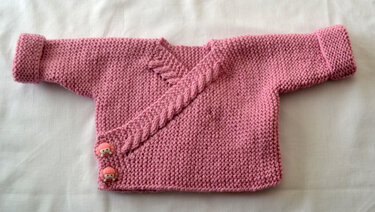 Rosa gestrickte Baby-Wickeljacke mit diagonalem Zopfmuster und zwei rosa Knöpfen