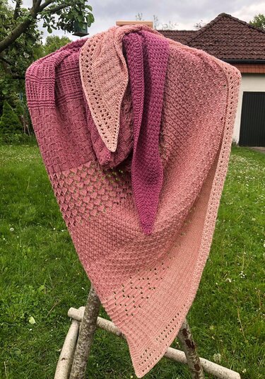Dreieckstuch mit kombinierten Strickmustern: Lochmuster, kraus rechts und strukturierte Maschen, aufgehängt im Garten