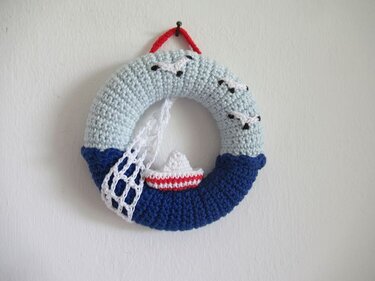 Gehäkelter blauer Türkranz mit kleinem Boot, Netz und Möwen