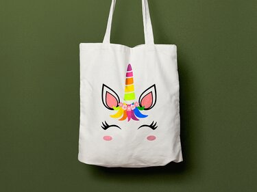 Weiße Stofftasche mit buntem Einhorn-Gesicht, Regenbogenhorn und Blumenkranz