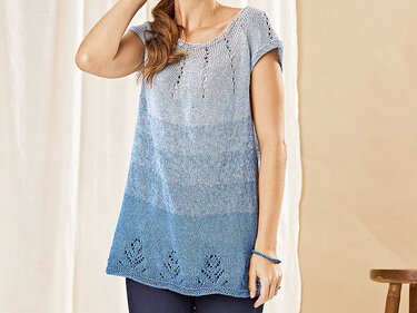 Frau trägt kurzärmeliges Stricktop in A-Linie mit Hellgrau-zu-Blau-Farbverlauf und Ajourmuster am Saum