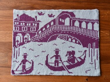 Two-color knitted panel showing gondolas on a canal with an arched bridge and waterfront buildings
