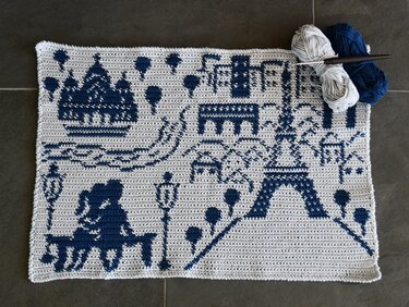 Tapestry crochet panel in cream and navy with yarn skeins and crochet hook