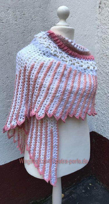 White and pink crocheted shawl with diagonal stripes and scalloped edge on a mannequin, showing stitch detail.
