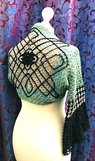 Rückansicht gehäkelter Damenbolero in Grün, Hellgrau und Schwarz mit Rautenmuster und Glockenärmeln auf Schaufensterpuppe