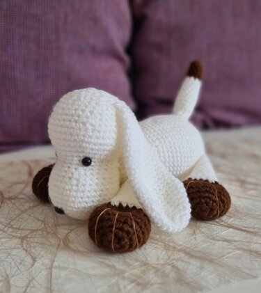 Weißer Amigurumi-Hund mit braunen Pfoten, Schwanzspitze und Schlappohren