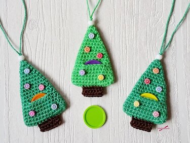 Drei gehäkelte Tannenbaum-Anhänger mit Blüten, Chipfach, Kordel und weißer Perle.