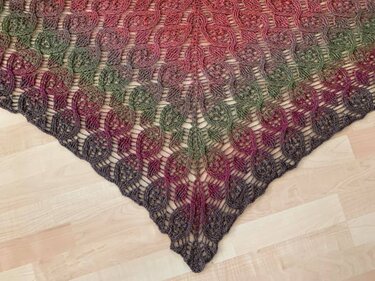 Gehäkeltes Dreieckstuch in Multicolor mit filigranem Spitzenmuster auf hellem Holzboden