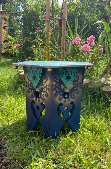 Blauer Holz-Beistelltisch mit gold- und türkisfarbenen Ornamenten und ausgeschnittenen Verzierungen auf Rasen
