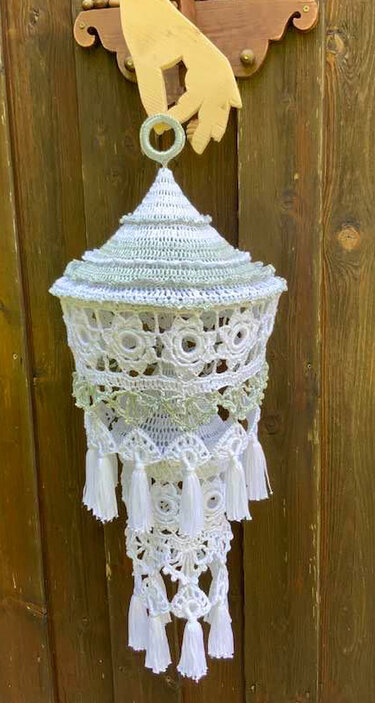 Weißer gehäkelter Hänger mit floralen Mustern und Quasten an einer Holzaufhängung