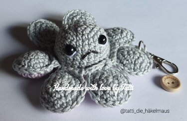 Gehäkelter hellgrauer Oktopus-Schlüsselanhänger mit schwarzen Sicherheitsaugen und Metallkarabiner