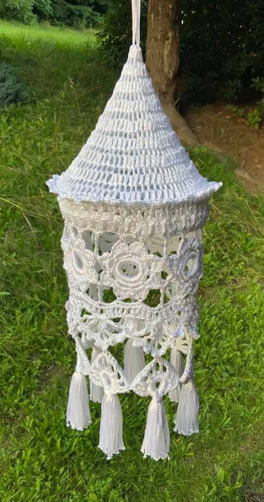 weiß gehäkelter Lampion mit spitzer Kappe, floralen Häkelmotiven und Quasten, hängend