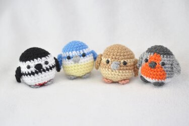 Vier gehäkelte Amigurumi-Vögel: schwarz-weiß, Blaumeise, Spatz, Rotkehlchen.