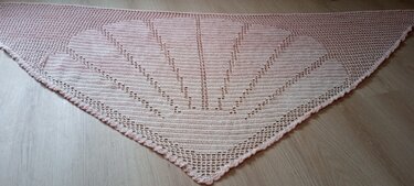 Zartrosa gehäkeltes Dreieckstuch mit Fächermuster, liegend auf Holz