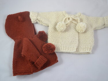 Gestrickte Babyjacken in Rostrot und Creme mit Bommeln