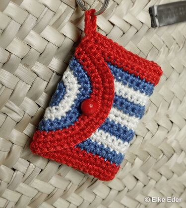 Crocheted keychain pouch with red, white and blue stripes and a red button flap.