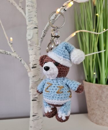 Gehäkelter Teddybär in blauem Schlafanzug als Schlüsselanhänger an Metallring