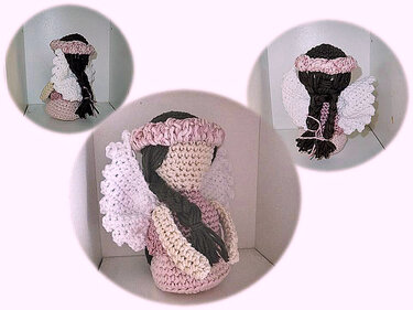 Gehäkeltes Amigurumi-Engelchen mit geflochtenem dunklem Zopf, rosa Stirnband und weißen Flügeln, sitzend