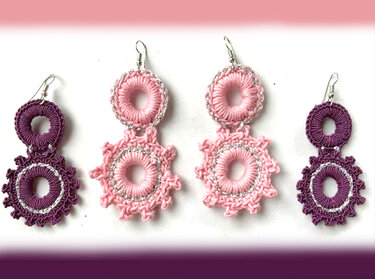 Vier gehäkelte Ohrringe, zwei rosa, zwei lila, mit silberfarbenen Details auf weißem Hintergrund.