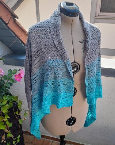 Offene gehäkelte Jacke in Grau und Türkis auf einer Schneiderpuppe mit Ombré‑Verlauf