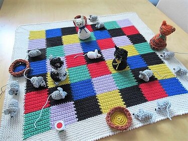 Bunte gehäkelte Karodecke mit kleinen gehäkelten Katzen, Mäusen und Napfschalen
