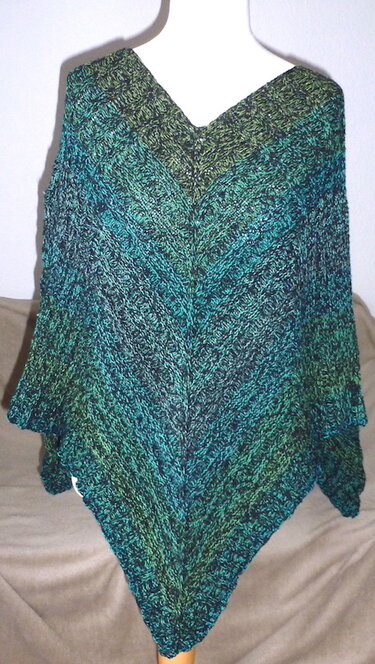 Gestrickter V‑förmiger Poncho in Grün‑ und Petroltönen auf Schaufensterpuppe