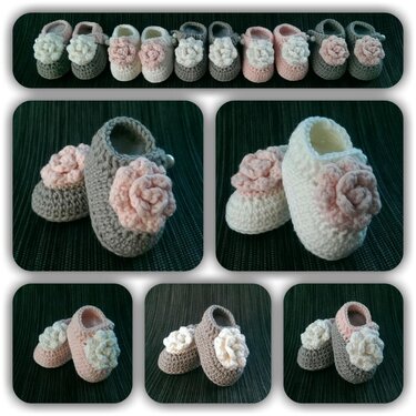 Eine Reihe gehäkelter Babyschuhe in Grau, Weiß und Rosa, verziert mit gehäkelten Blumen.