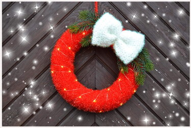 Roter gehäkelter Weihnachtskranz mit weißer Schleife an dunkler Holztür