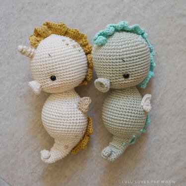 Pair of crocheted seahorse amigurumi in cream and sage with ruffled manes