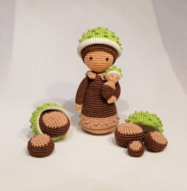 Gehäkelte Kastanienfiguren: große Puppe mit Baby, grüne Hütchen, lose Kastanien und Hüllen.