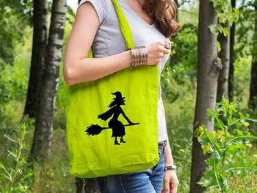 Grüne Tragetasche mit schwarzer Silhouette einer Hexe auf ihrem Besen