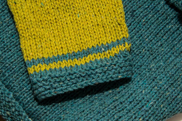 Detailaufnahme eines Strickmusters mit gelben und petrolfarbenen Streifen
