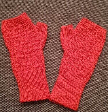 Paar korallenrote, gestrickte fingerlose Handstulpen mit Rippbündchen