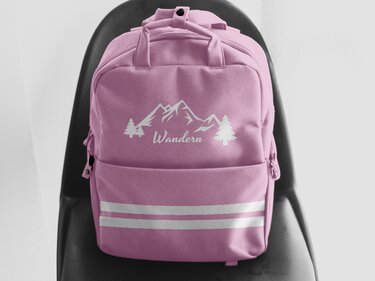 Pinker Rucksack, personalisierbar mit weißem Plottermotiv (Berge, Tannen, „Wandern“) und reflektierenden Streifen