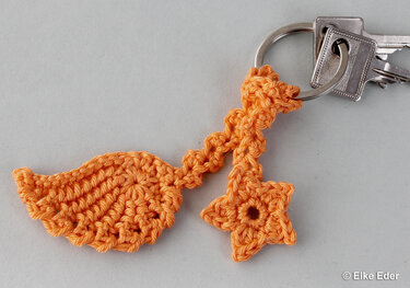 Orange crocheted keychain with a wing shape and a star charm on a metal key ring.