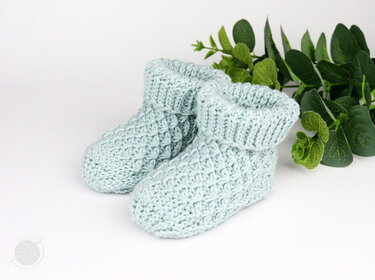 Pair of pale mint crocheted baby booties with textured stitch and fold-over ribbed cuffs
