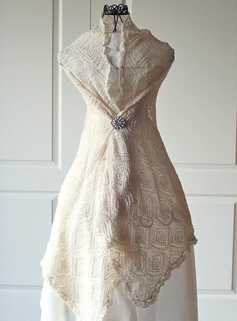 Elfenbeinfarbenes gestricktes Lacetuch mit Rautenmuster, auf Büste drapiert und mit Brosche befestigt