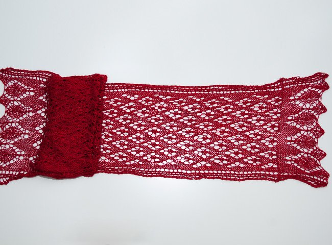 Rotes Lacetuch mit filigranem Lochmuster auf hellem Hintergrund