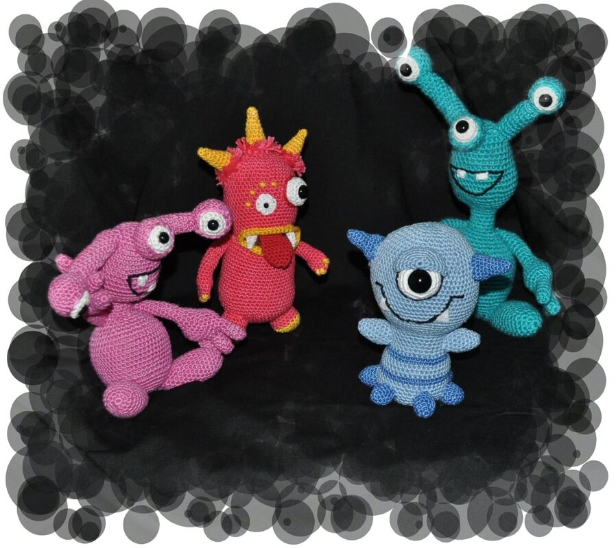 Vier gehäkelte Amigurumi-Monster: pink, rot, hellblau, türkis auf dunklem Grund.