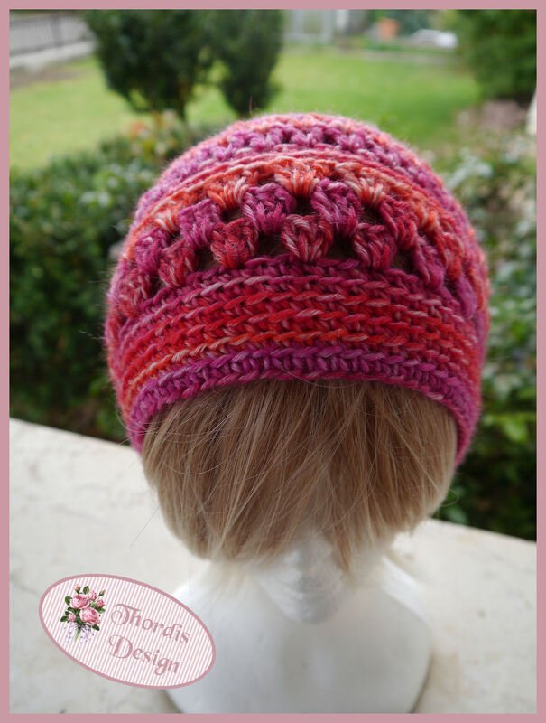 Rückansicht einer gehäkelten Damenmütze in Rosa- und Orangetönen auf Schaufensterkopf