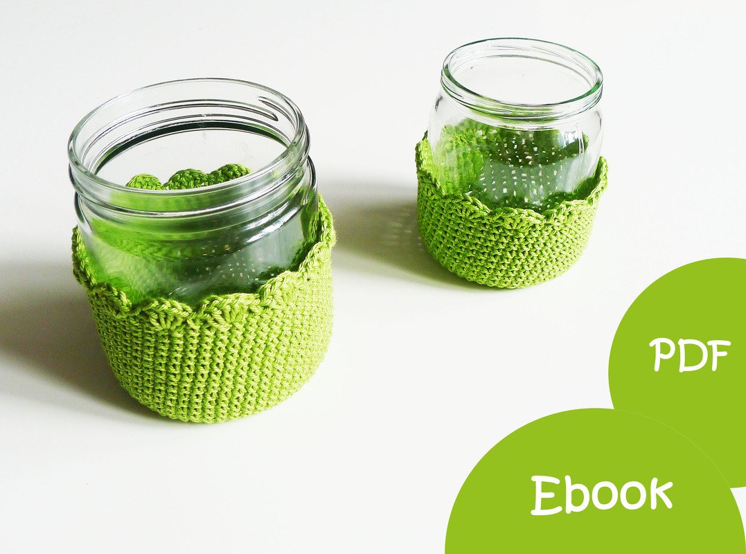 Zwei klare Gläser mit hellgrünen, gehäkelten Überzügen auf weißem Untergrund